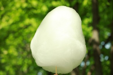 Photo of One sweet cotton candy against blurred green, closeup