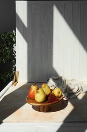 Photo of Stand with juicy pears, red currants and double-sided backdrop on table in photo studio