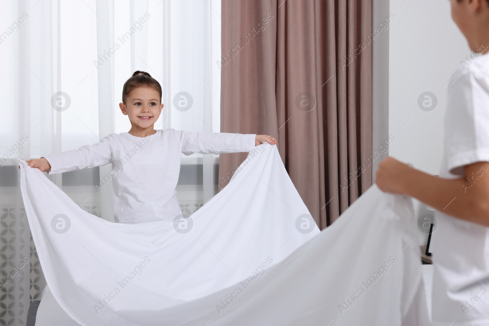 Photo of Brother and sister changing bed linens together in bedroom