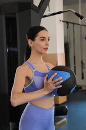 Sporty woman with medicine ball in modern gym