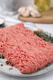Photo of Fresh raw ground meat and peppercorns on white tiled table, closeup