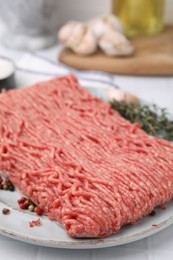 Fresh raw ground meat and peppercorns on white tiled table, closeup