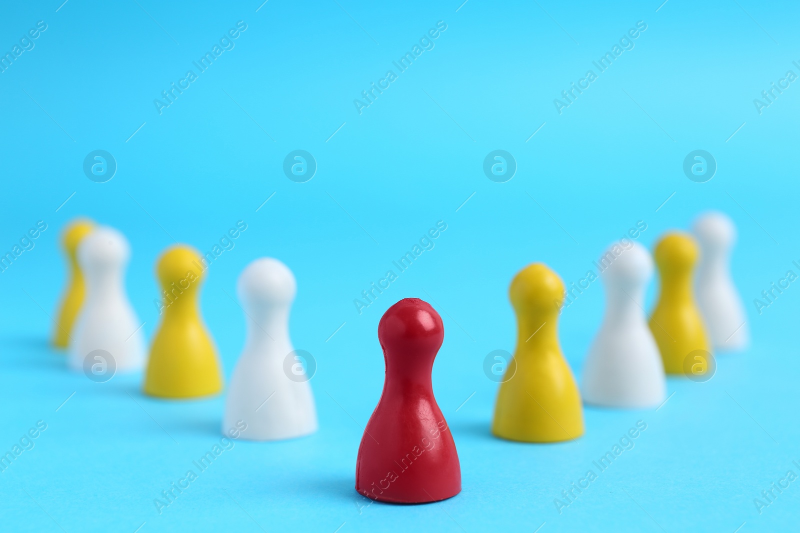 Photo of Red playing piece with following group on light blue background. Roles and responsibility concept