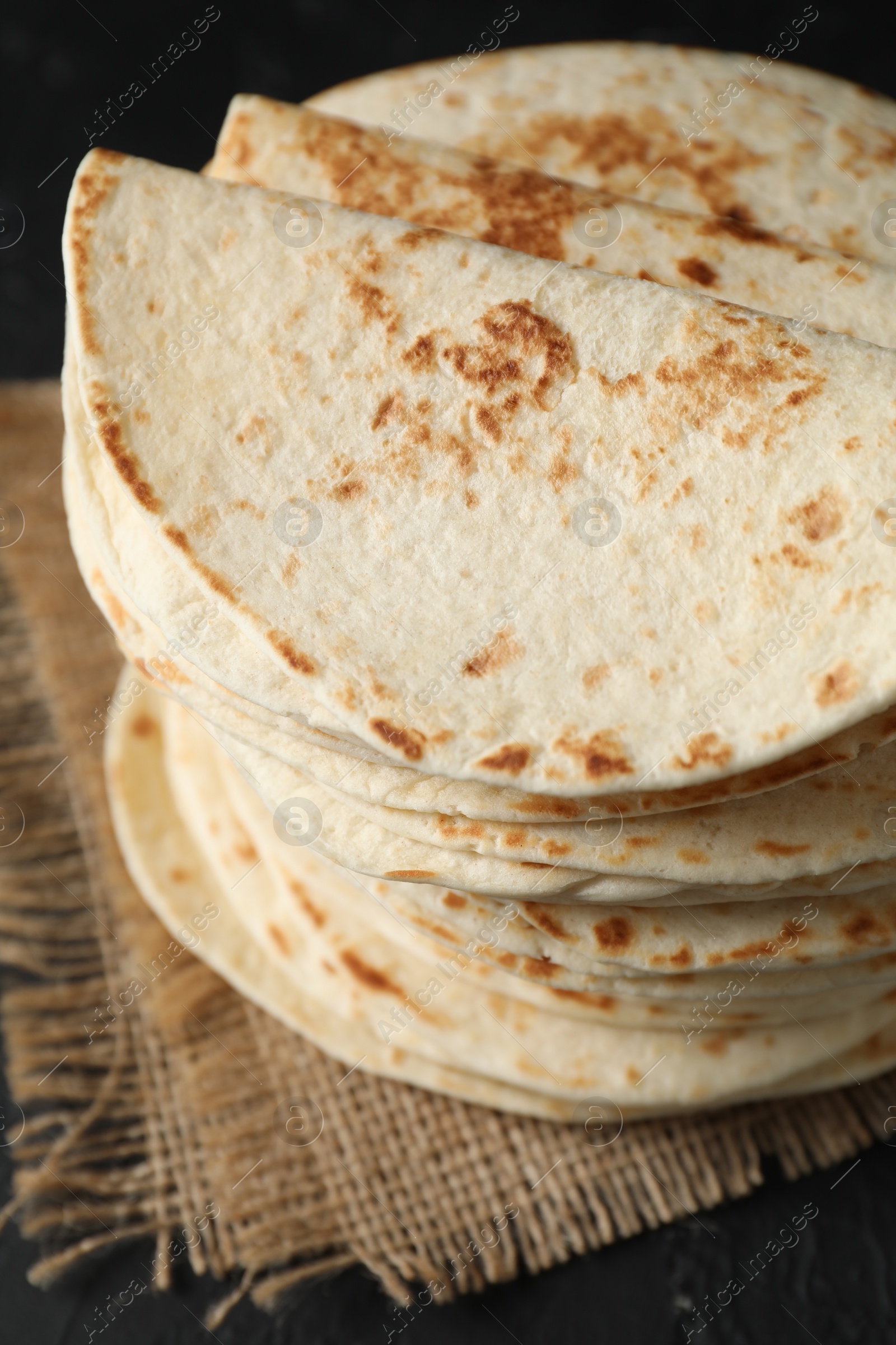 Photo of Stack of tasty homemade tortillas on black table