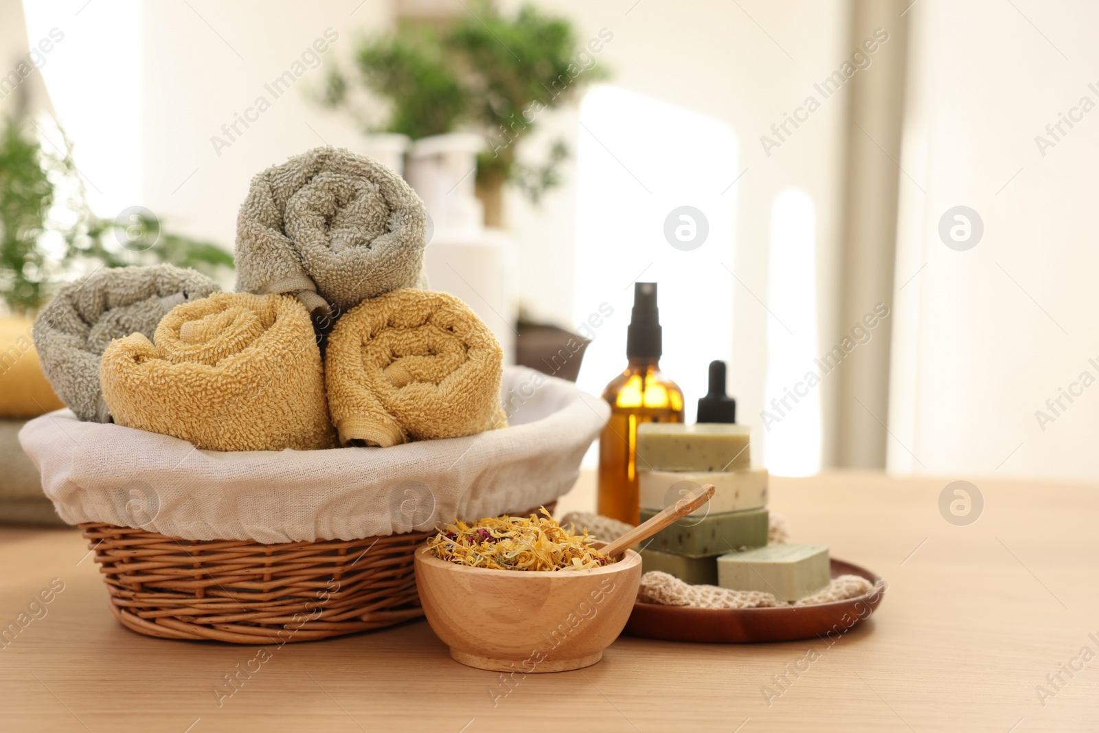 Photo of Dry flowers, soap bars, bottles of essential oils, jar with cream and towels on wooden table indoors, space for text. Spa time