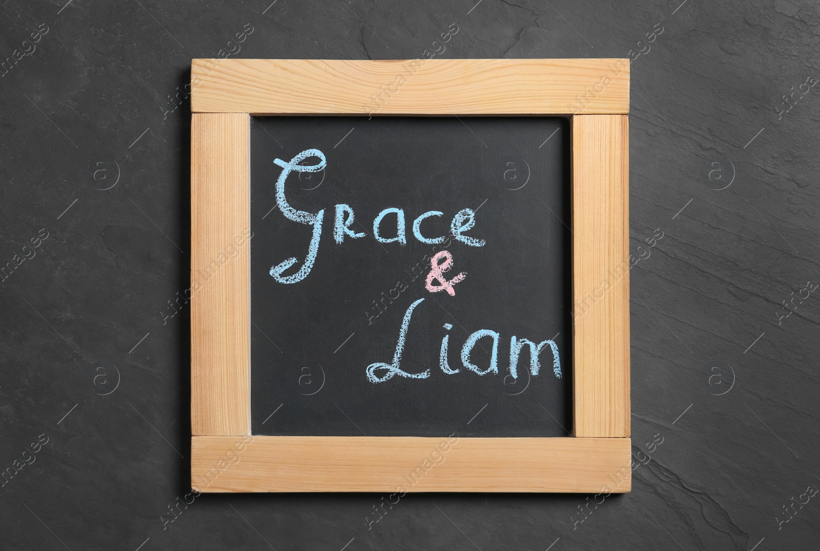 Photo of Blackboard with baby names on black stone table, top view