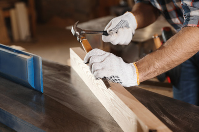 Photo of Professional carpenter working with wooden plank in workshop, closeup