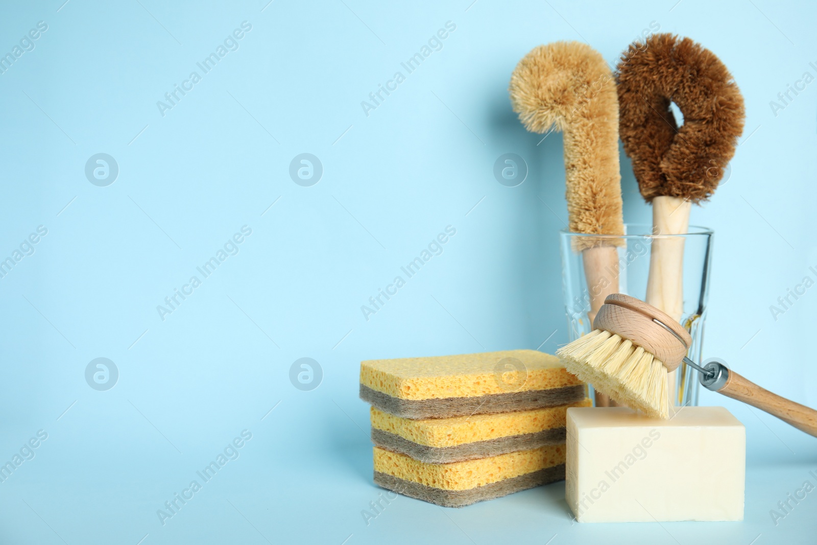 Photo of Cleaning tools on light blue background, space for text. Dish washing supplies