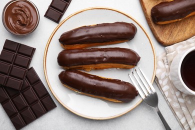 Photo of Delicious eclairs and chocolate on grey table, flat lay