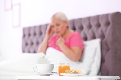 Photo of Tea with cough remedies and ill woman on background