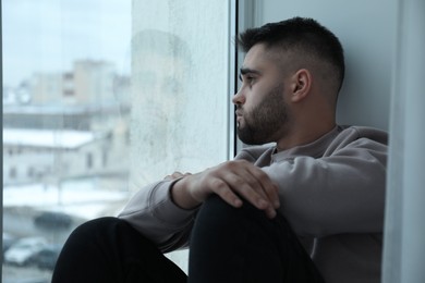 Sad man looking at window at home