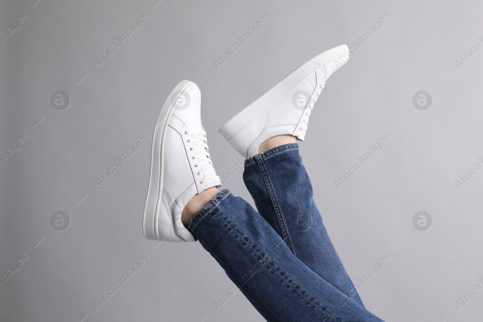 Photo of Man wearing stylish white sneakers on grey background, closeup