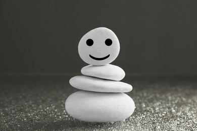 Photo of Stack of stones with drawn happy face on grey background. Zen concept
