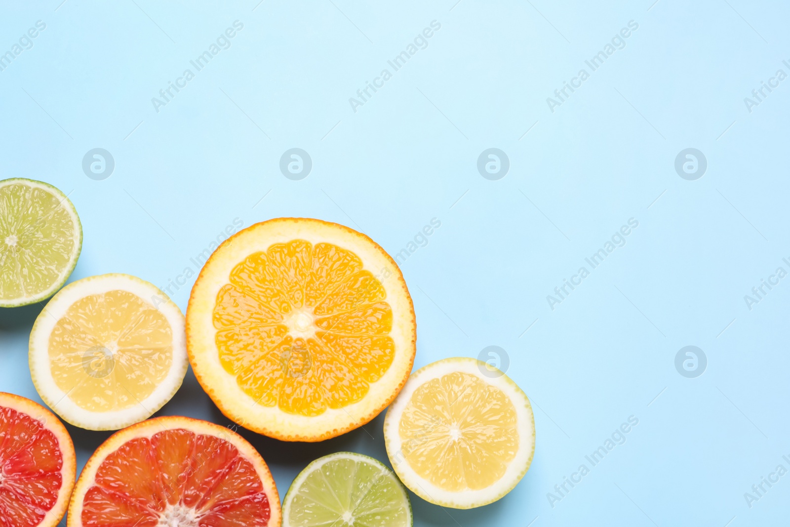 Photo of Fresh juicy citrus fruits on light blue background, flat lay. Space for text