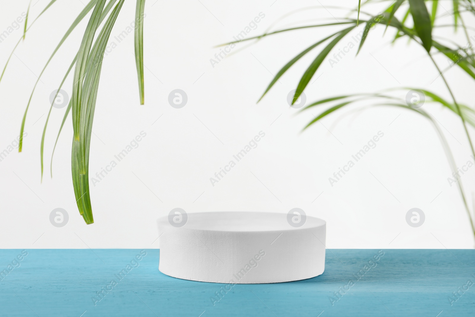 Photo of Round shaped podium on light blue wooden table. Space for text