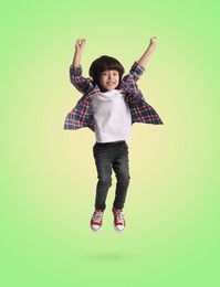 Image of Happy boy jumping on color gradient background