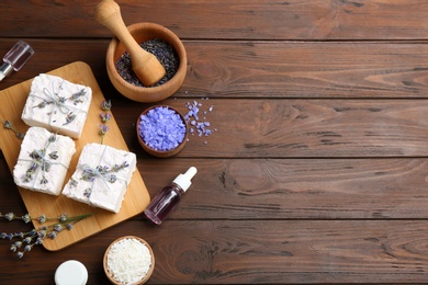 Photo of Flat lay composition with hand made soap bars and lavender flowers on wooden table, space for text