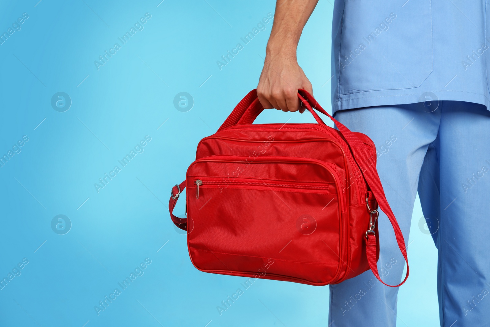 Photo of Male doctor with first aid kit and space for text on color background, closeup. Medical object