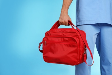 Male doctor with first aid kit and space for text on color background, closeup. Medical object