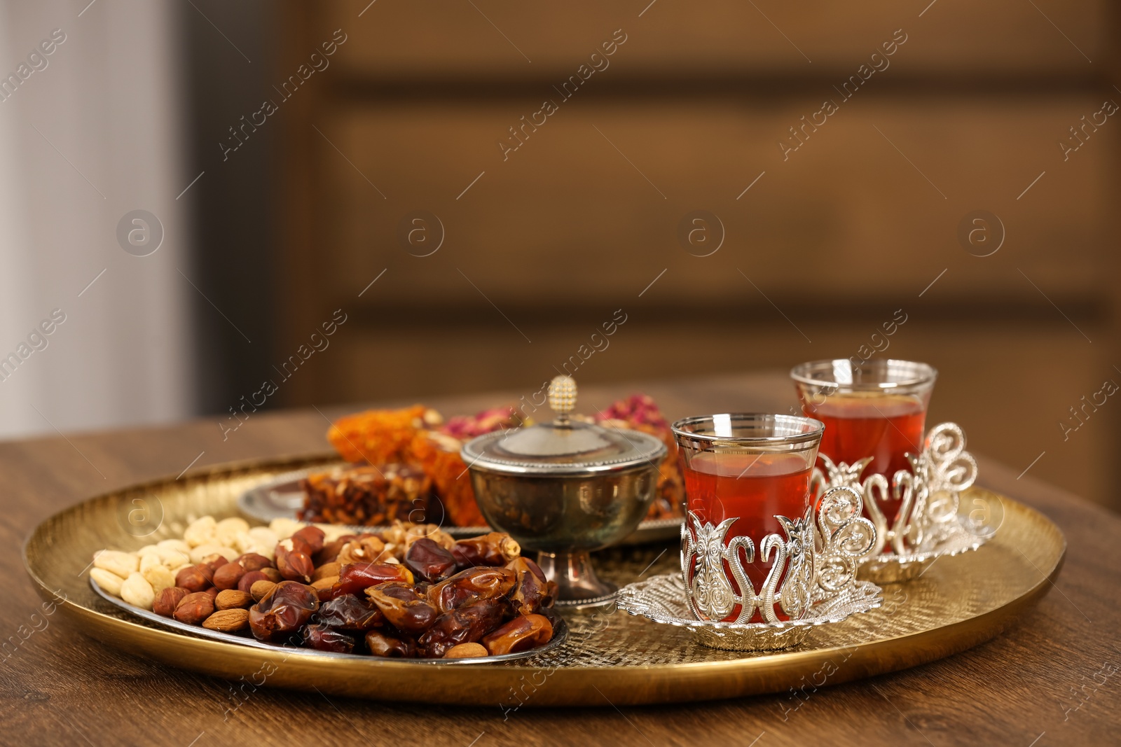 Photo of Glasses with tasty Turkish tea and oriental sweets on wooden table indoors, space for text