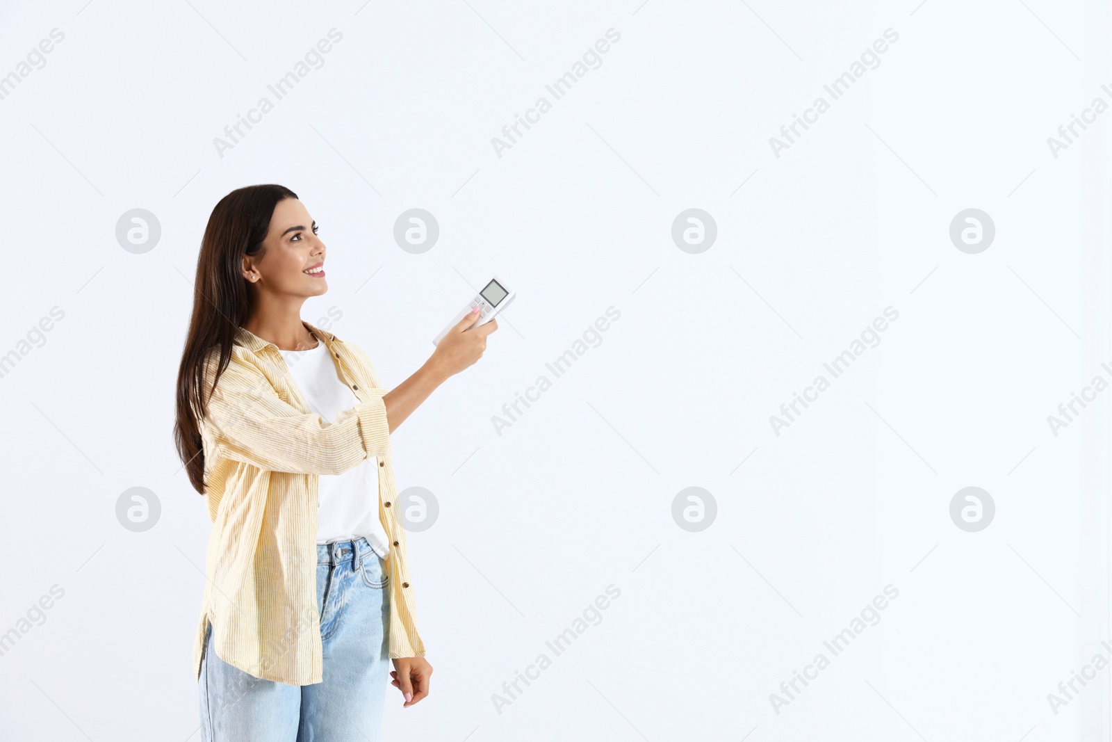 Photo of Young woman turning on air conditioner against white background