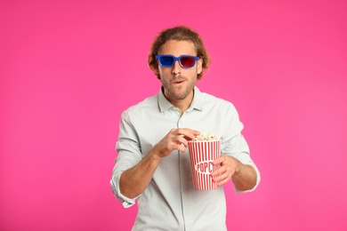 Photo of Man with 3D glasses and popcorn during cinema show on color background