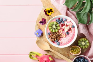 Flat lay composition with tasty smoothie bowl on pink wooden table. Space for text