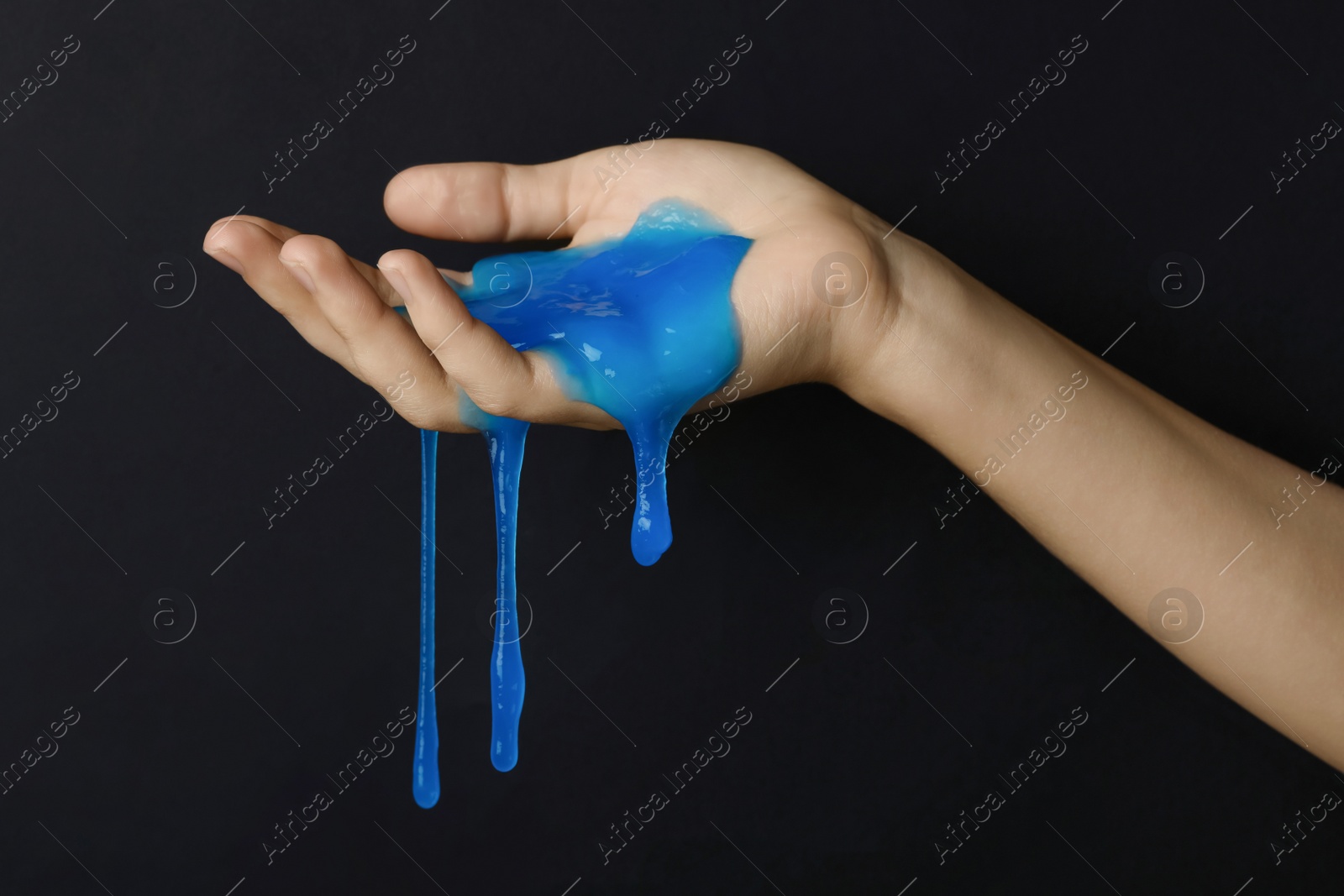 Photo of Woman playing with blue slime on black background, closeup. Antistress toy