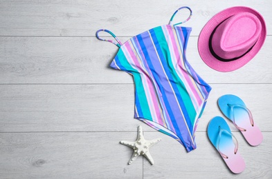 Photo of Flat lay composition with one-piece swimsuit and beach objects on wooden background