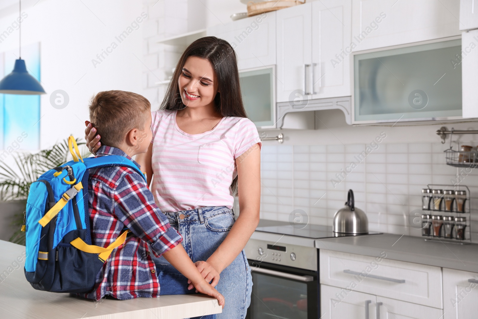 Photo of Happy mother and little child with backpack ready for school in kitchen