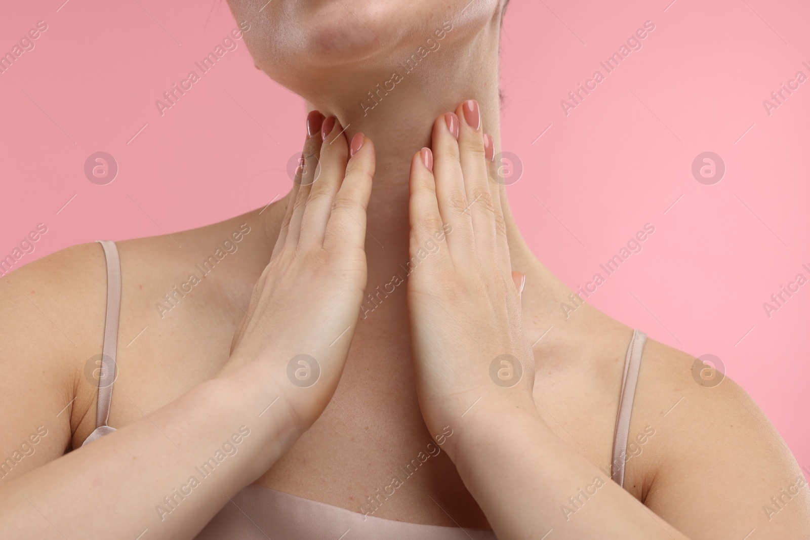 Photo of Woman touching her neck on pink background, closeup