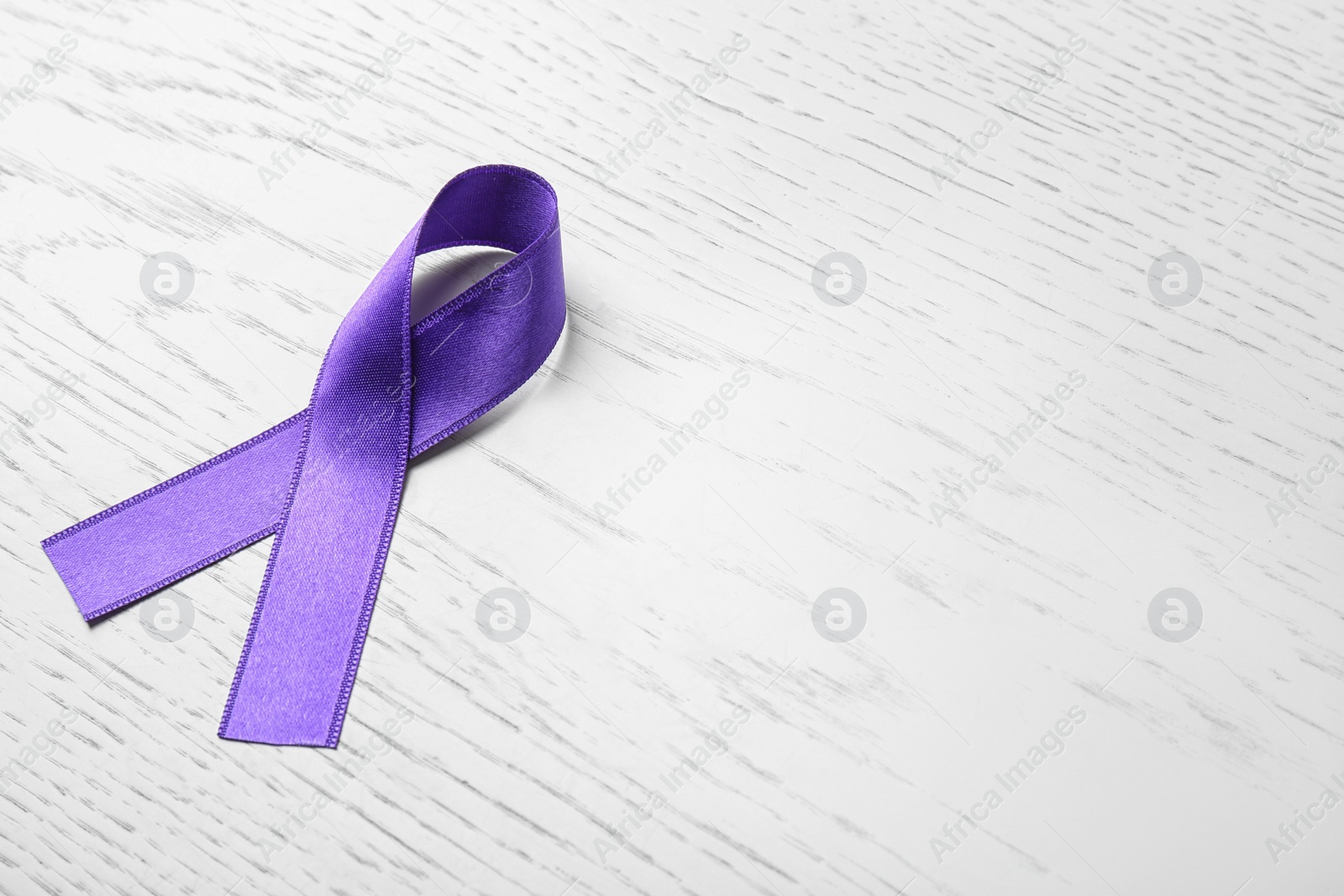 Photo of Purple ribbon on white wooden background, space for text. Domestic violence awareness
