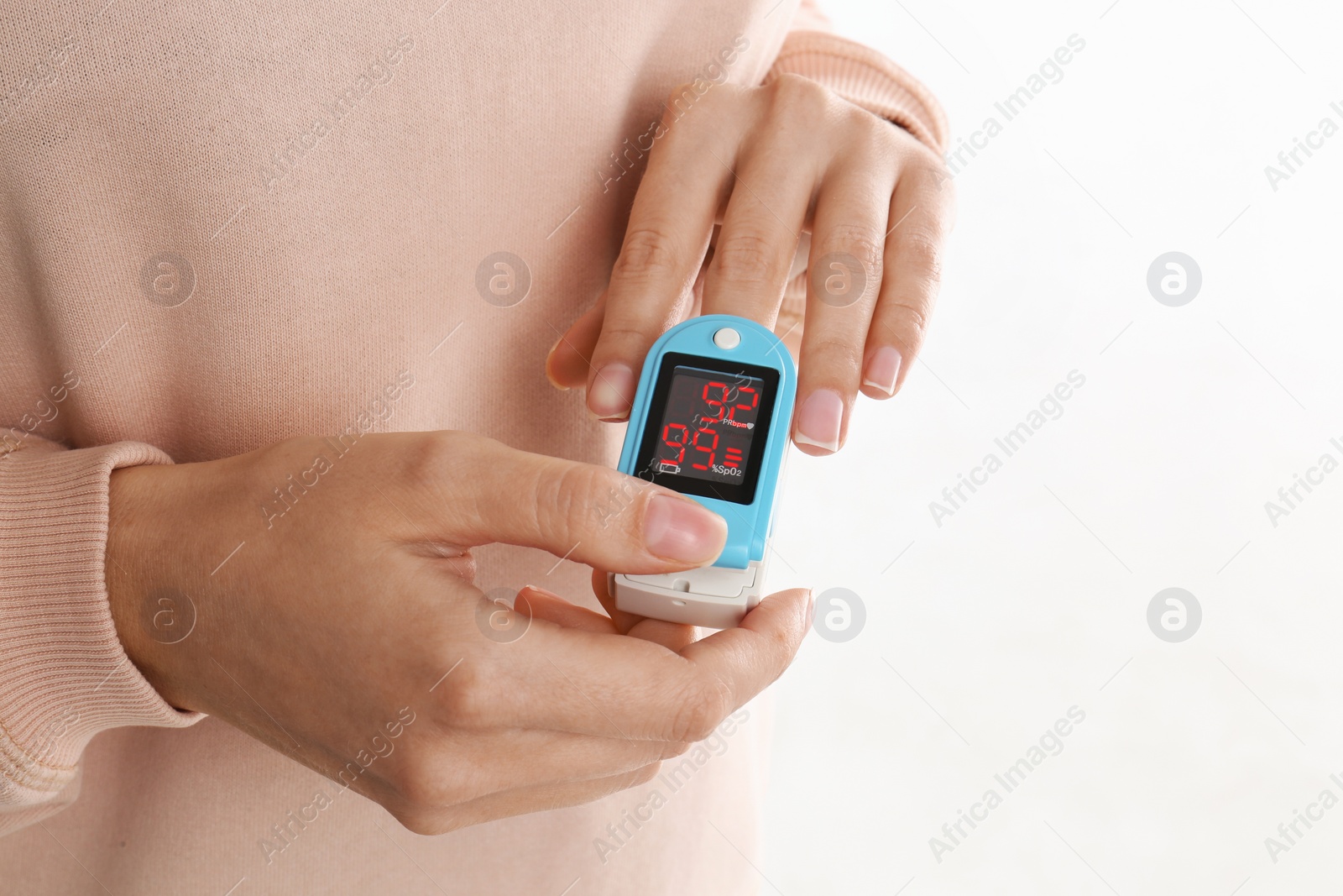 Photo of Woman using pulse oximeter for oxygen level testing on white background, closeup