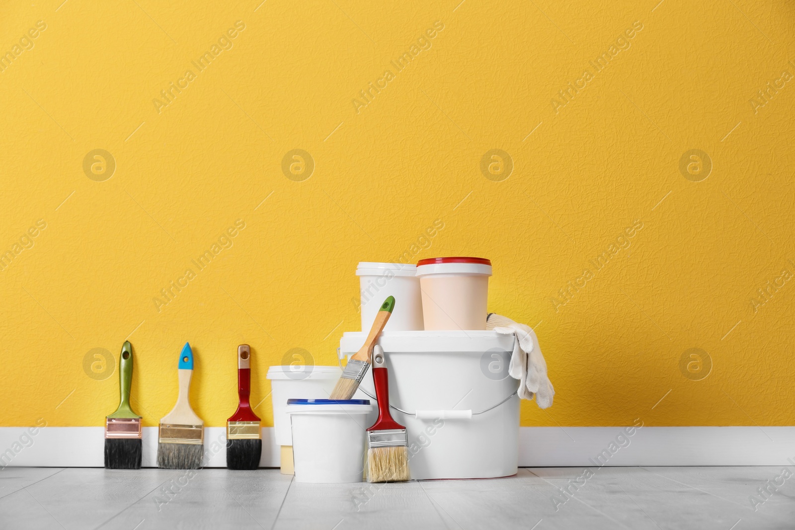 Photo of Set with decorator tools and paint on floor near color wall