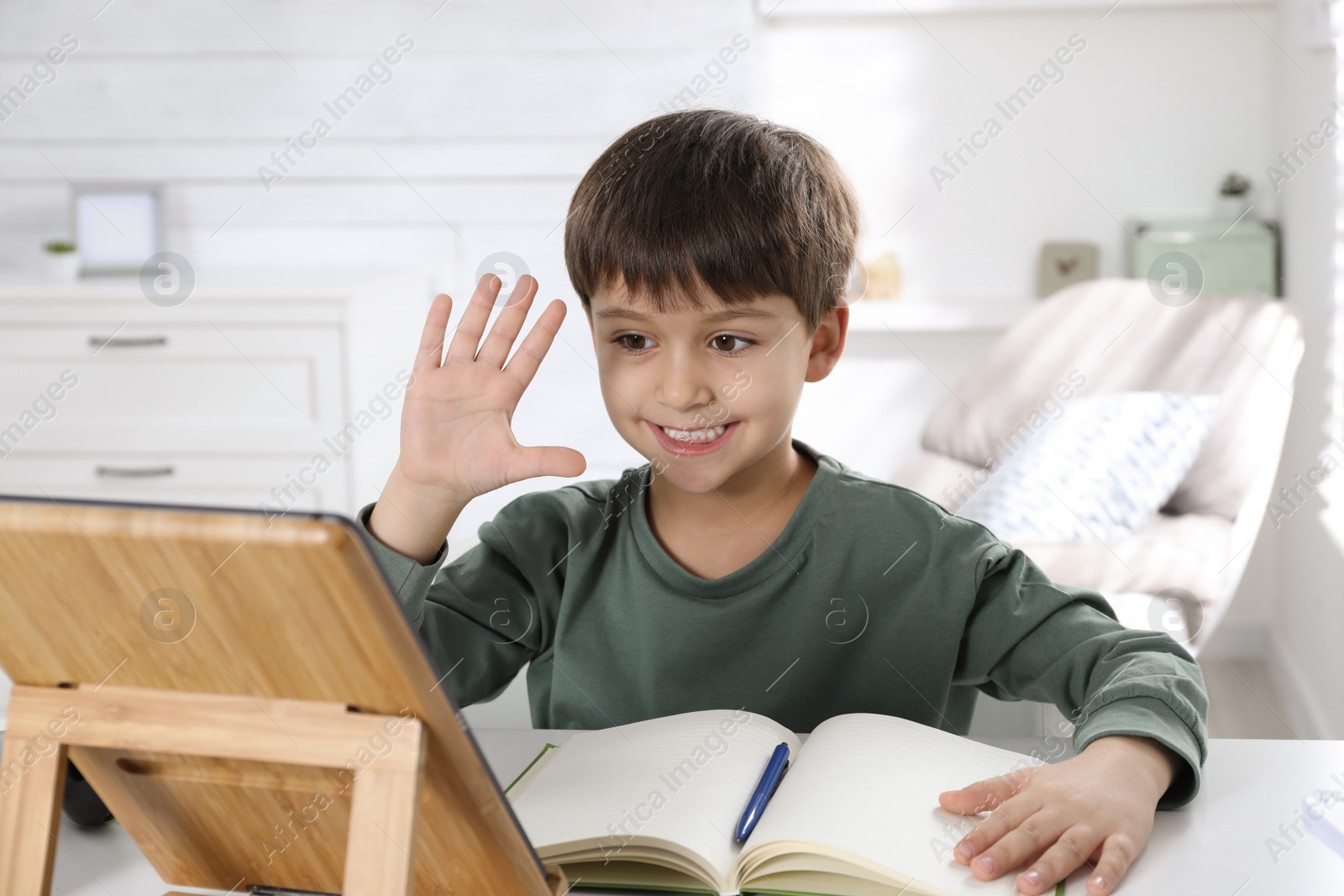 Photo of Cute little boy with modern tablet studying online at home. E-learning