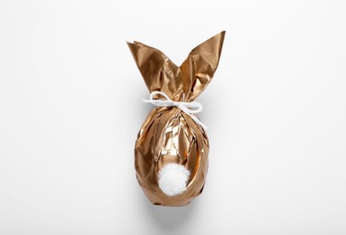 Easter bunny made of shiny gold paper and egg on white background, top view