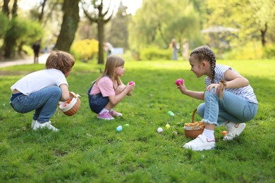 Photo of Easter celebration. Cute little children hunting eggs outdoors