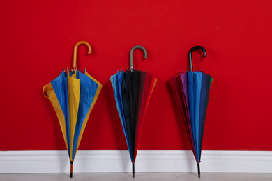 Beautiful closed colorful umbrellas near red wall