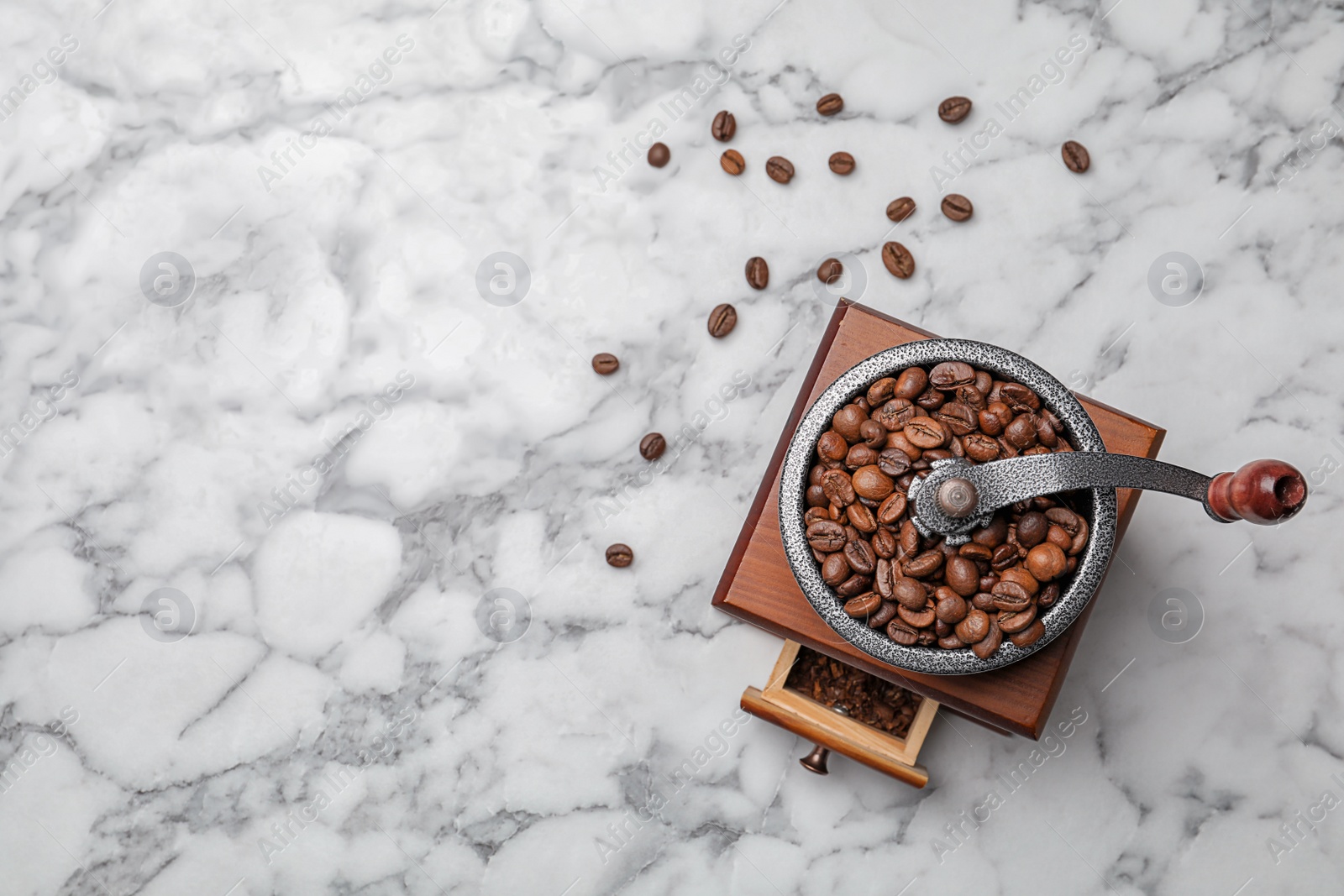 Photo of Retro coffee grinder with beans on marble background, top view