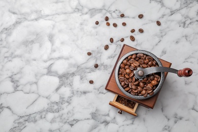 Photo of Retro coffee grinder with beans on marble background, top view