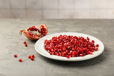 Photo of Tasty ripe pomegranate grains on grey table