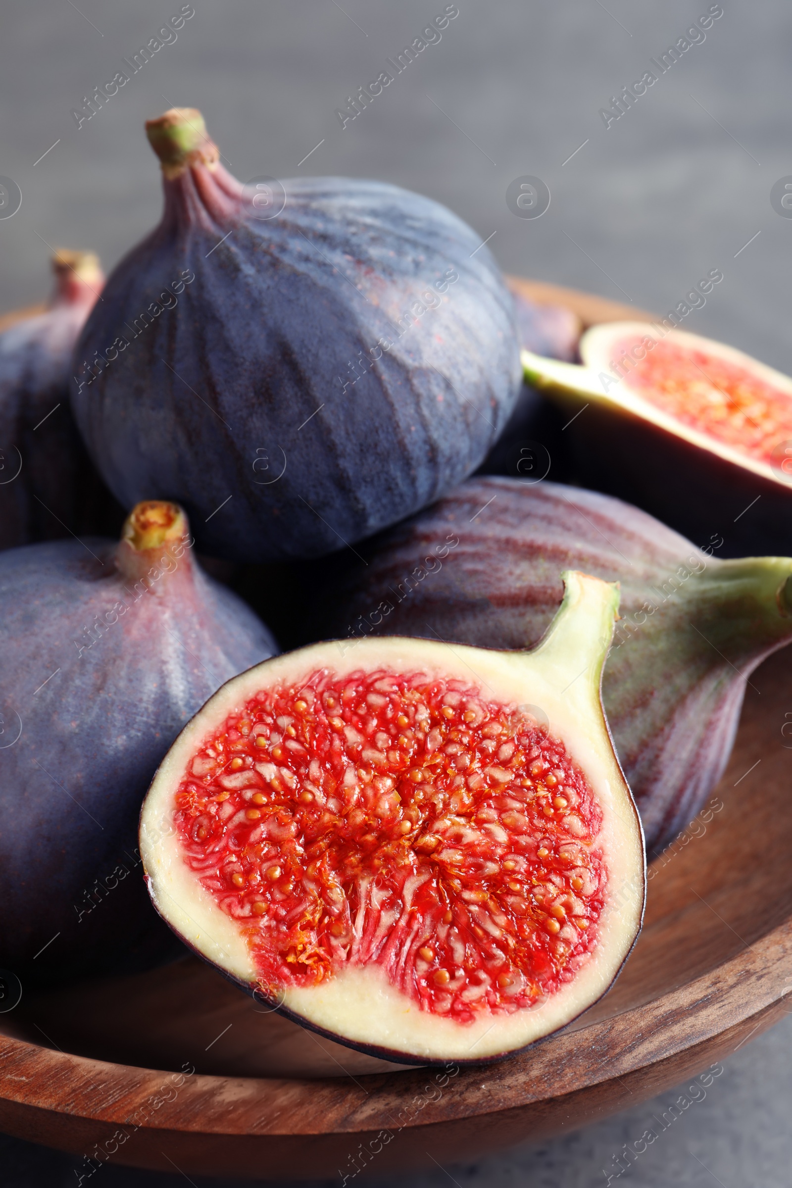 Photo of Bowl with fresh ripe figs on gray background. Tropical fruit