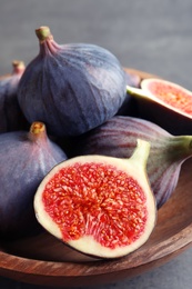 Bowl with fresh ripe figs on gray background. Tropical fruit