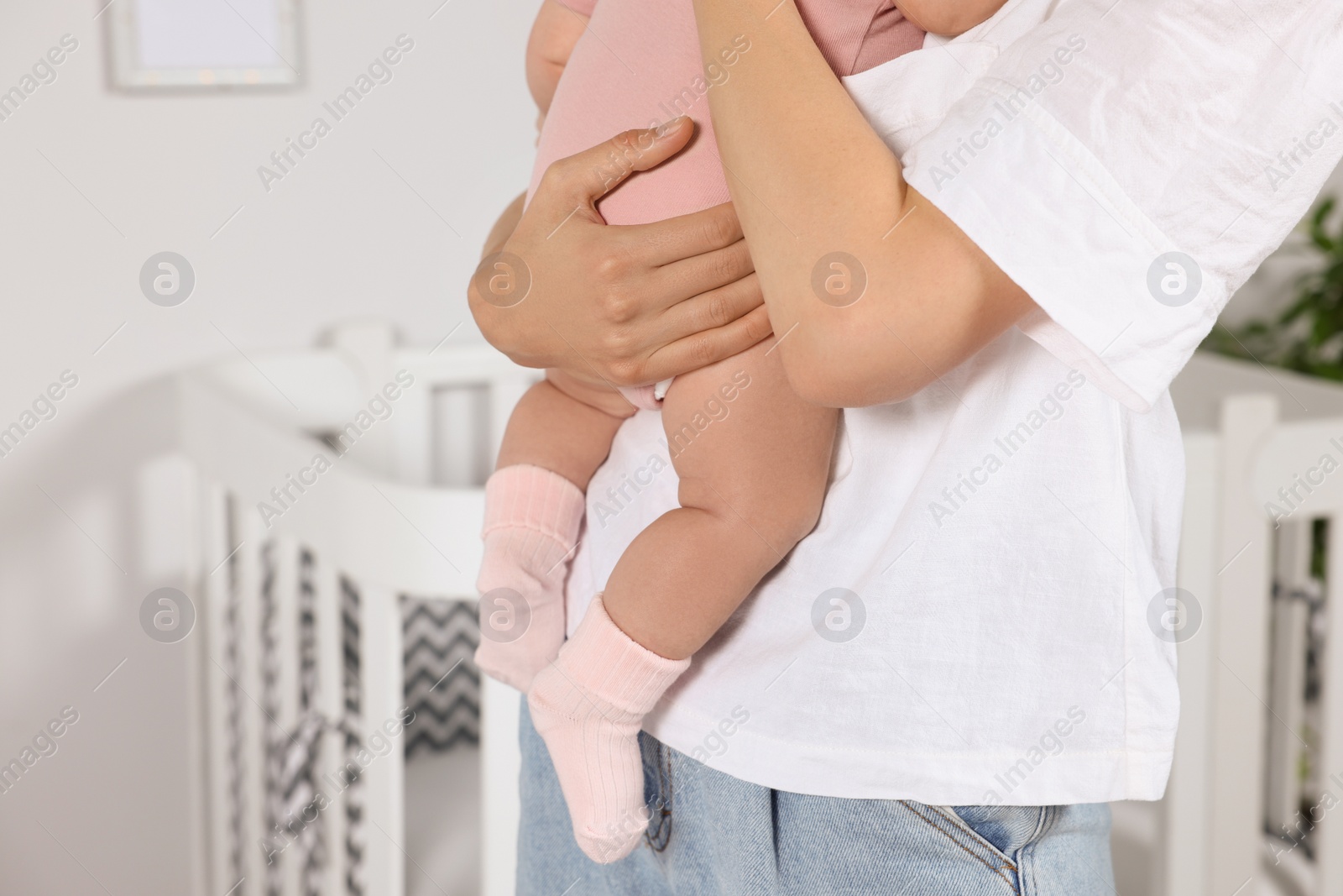 Photo of Mother holding her little baby in bedroom, closeup