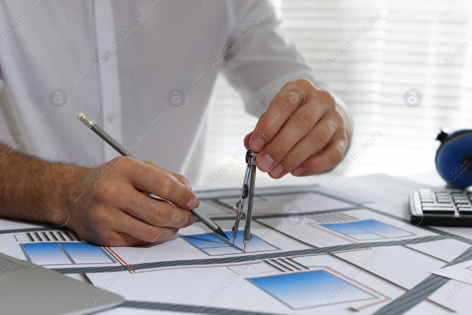 Photo of Architect working with construction drawings in office, closeup