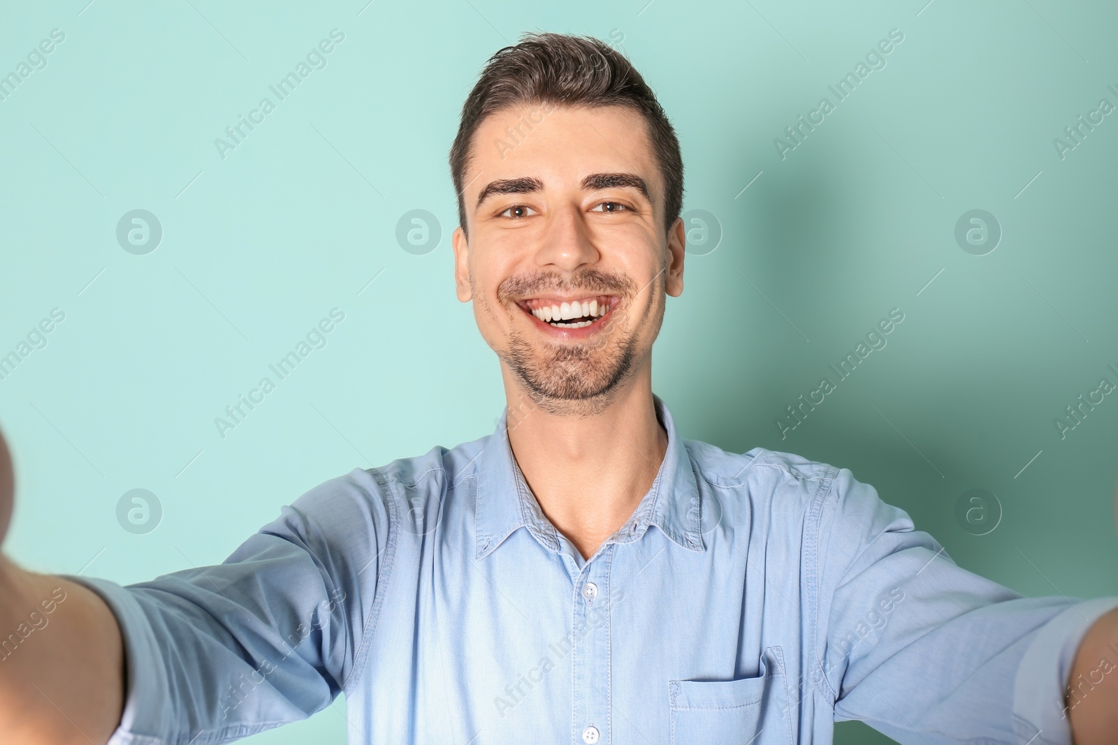 Photo of Young handsome man taking selfie against color background