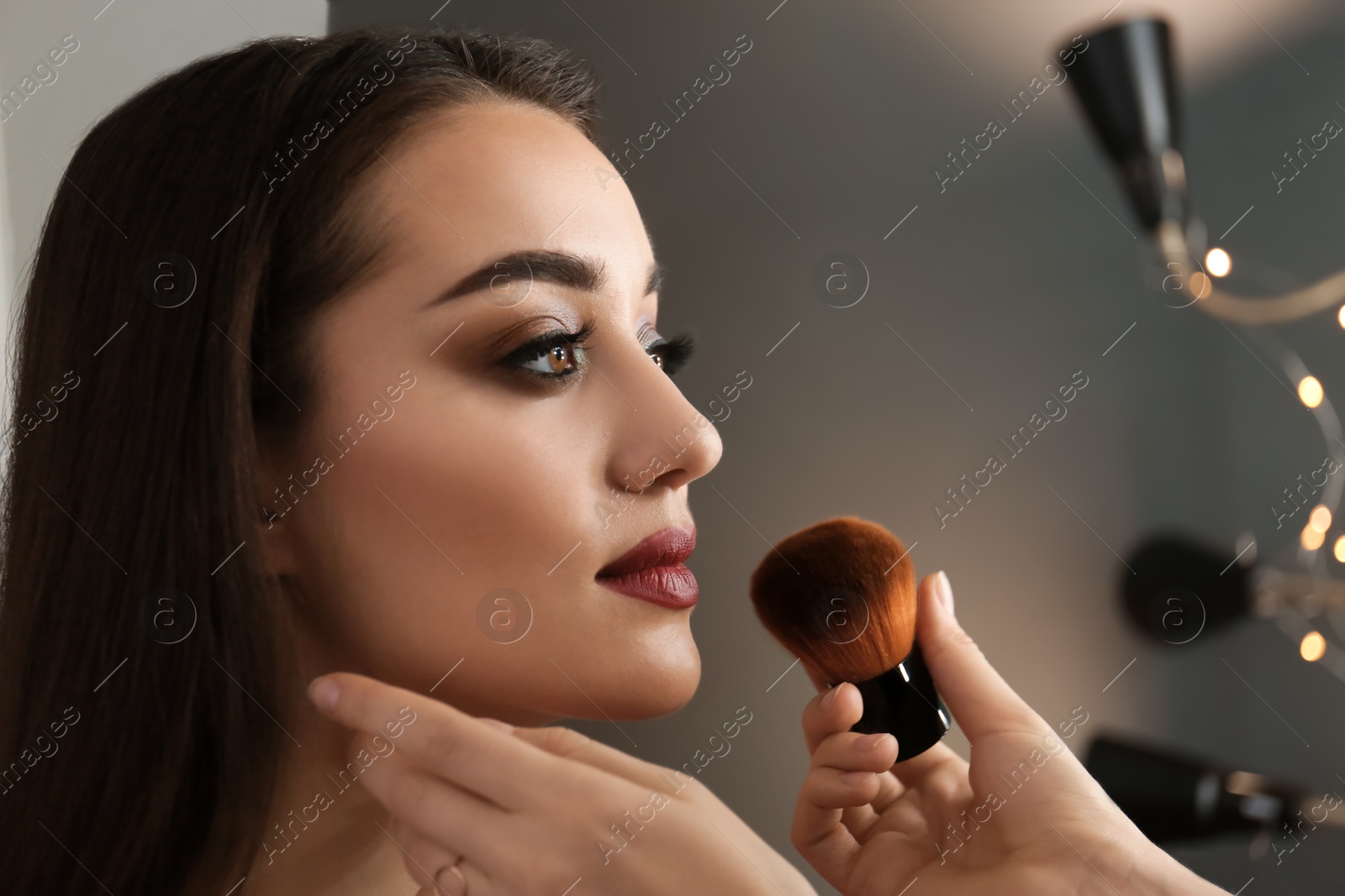 Photo of Professional visage artist applying makeup on woman's face in salon, closeup