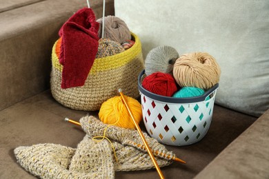 Photo of Soft woolen yarns, knitting and needles on brown sofa