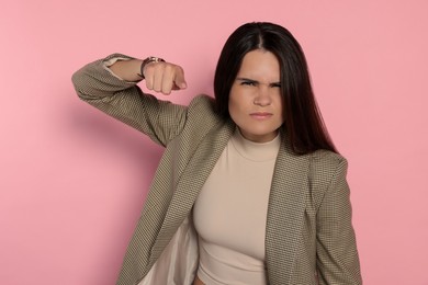 Aggressive young woman pointing on pink background