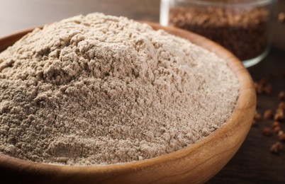 Photo of Bowl of buckwheat flour on wooden table, closeup